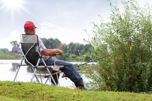 Fisherman fishes in the river. Middle aged man. 