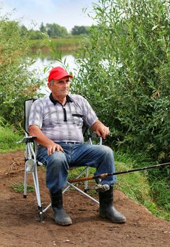 Fisherman fishes in the river. Middle aged man.