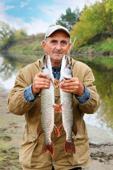 old fisherman and his catch - two pikes