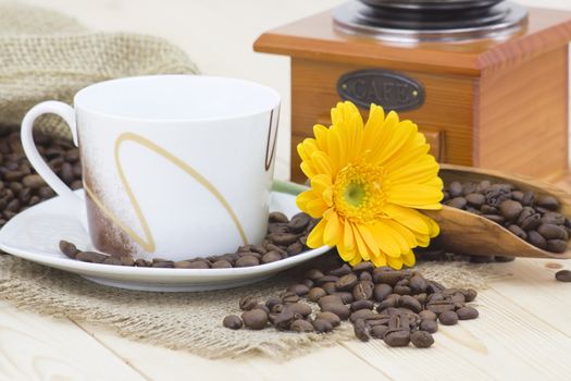 cup of coffee with yellow gerbera and coffee beans