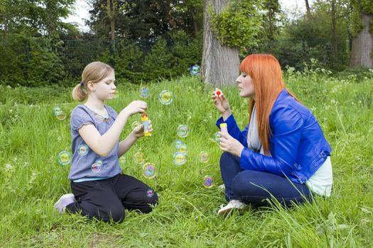 Little girl and young woman blowing soap bubbles