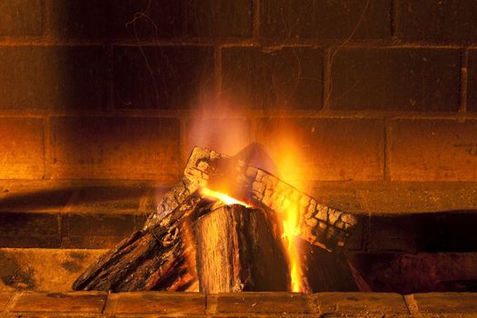 brick fireplace with large pieces of wood burning giving warmth