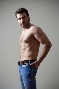 young shirtless musculous man in jeans looking - isolated on gray