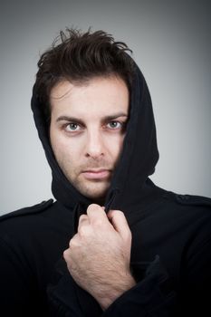 portrait of man in black top with hood looking at camera - isolated on gray