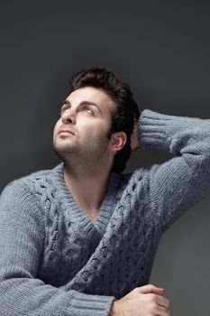 portrait of a man in a sweater lloking up - isolated on gray