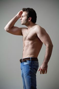 young shirtless musculous man in jeans looking - isolated on gray