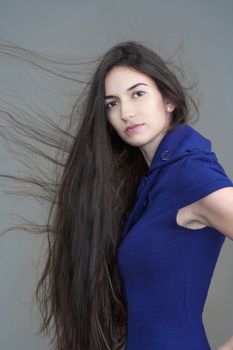 beautiful woman in blue dress with long brown hair flying - isolated on gray