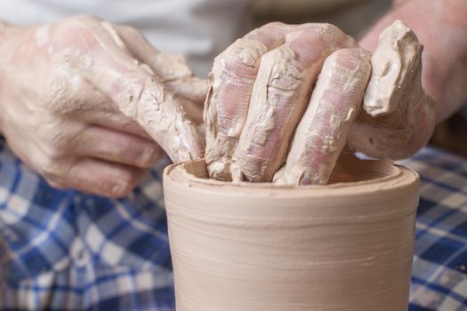 Hands of a potter, creating an earthen jar on the circle