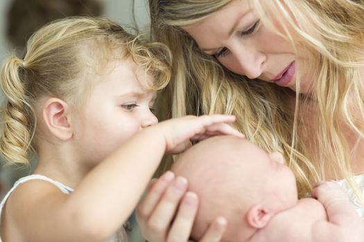 Beautiful Young Mother Holds Newborn Baby Girl as Young Sister Looks On.