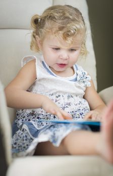 Adorable Blonde Haired Blue Eyed Little Girl Reading Her Book in the Chair.