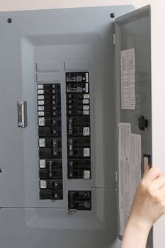 Woman checking automatic fuses at electrical control panel at home