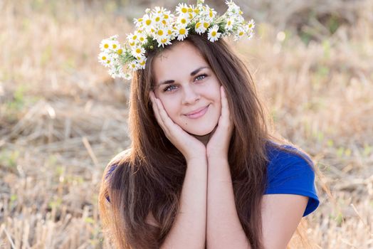 Teen girl with a wreath of daisies in a  field