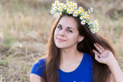 Teen girl with a wreath of daisies in a  field