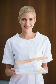 Smiling beauty therapist holding white towels at the spa