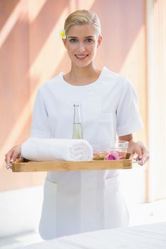 Smiling beauty therapist holding tray of beauty treatments at the spa