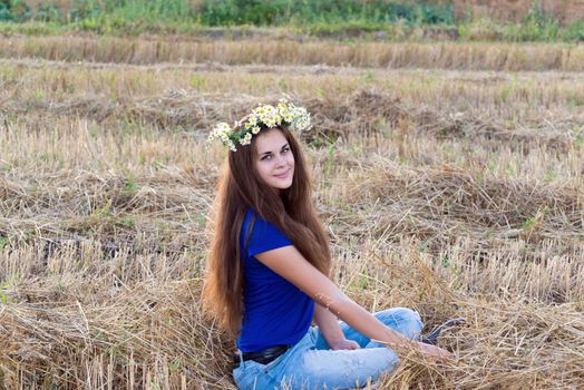 Teen girl with a wreath of daisies in a  field