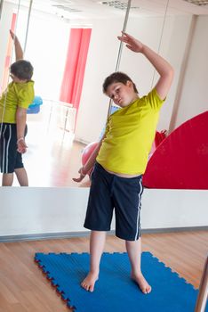 Boy does exercise with the ball in the gym