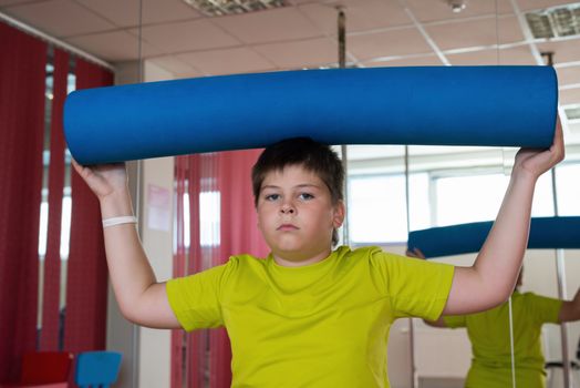 Boy does exercise with the ball in the gym