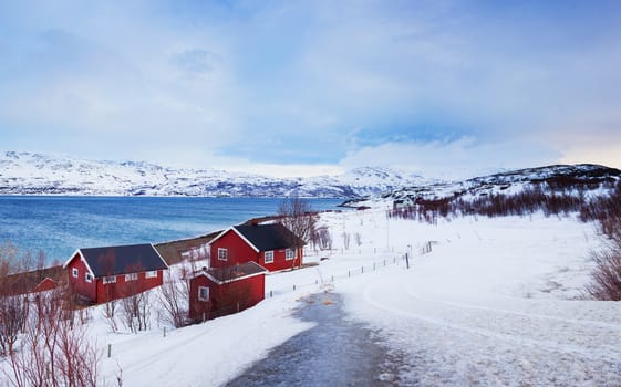 Winter in Norway - mountains with red house and the ocean.