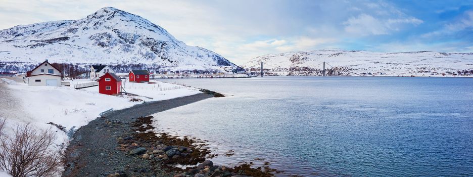 Winter in Norway - mountains with red house and the ocean.