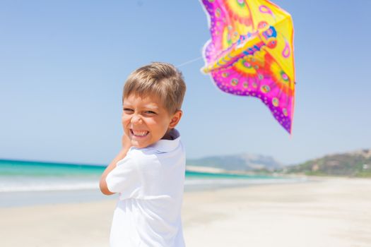 Summer vacation - Cute boy flying kite beach outdoor.