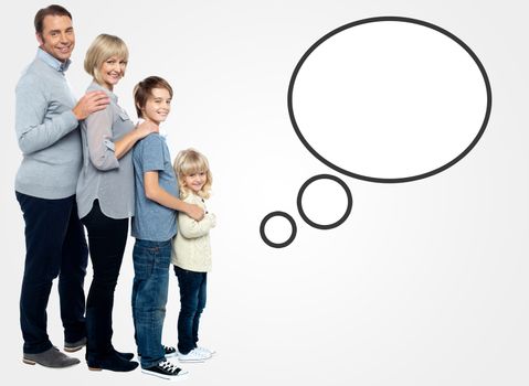 Smiling family of four posing with speech bubble
