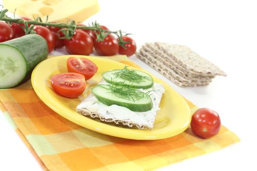 Crispbread with cream cheese and cucumber on a bright background