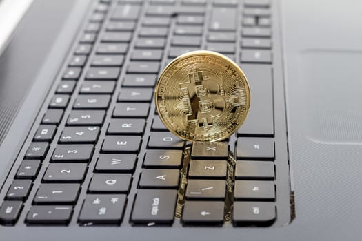 Studio shot of golden Bitcoin virtual currency on laptop. Close-up of front side. 