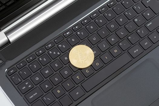 Studio shot of golden Bitcoin virtual currency on laptop. Close-up of front side.