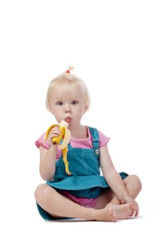 portrait of a little girl with blond hair eating banana - isolated on white