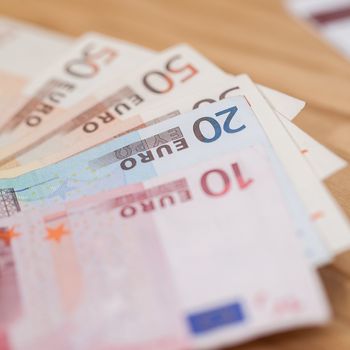 Heap of different euro banknotes on a wooden table