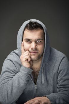 portrait of a young tough man with dark hair - isolated on dark gray