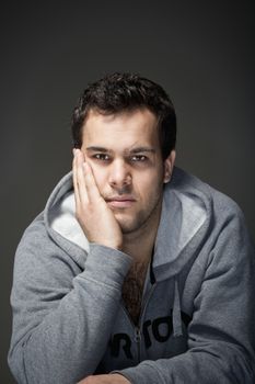 portrait of a young tough man with dark hair - isolated on dark gray