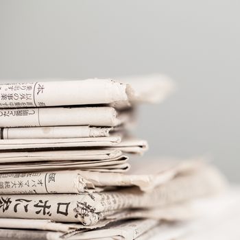 Pile of black and white newspapers on a wooden table