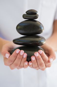 Beauty therapist holding pile of stones for massage at the spa