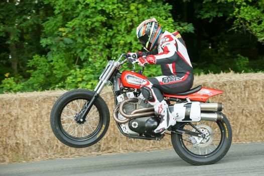 GOODWOOD, UK - JULY 1, 2012: World Superbike Champion James Toseland pulling a wheelie on a classic Harley Davidson XR750 motorcycle on the hill course at Goodwood on July 1, 2012