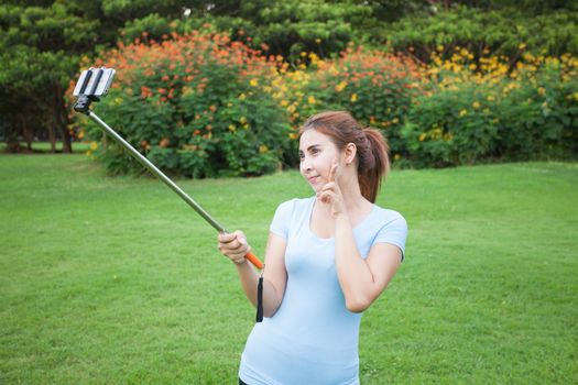 Pretty young female tourist takes travel selfie at the park