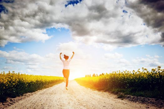 Happy young woman running and jumping for joy towards sun on the spring field Concepts of success, happiness, harmony, health, ecology