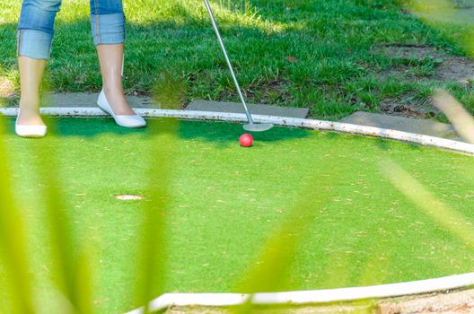 Close-up of a miniature golf course with feet racket red ball.
