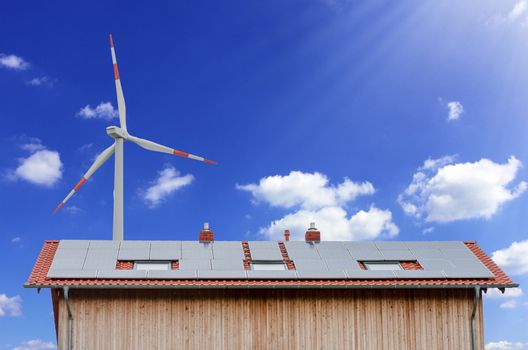 Solar panels and wind turbine against a sunny sky.