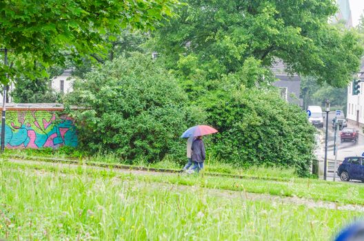 A pair älters in bad weather with umbrella.
