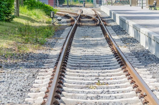 View on railroad tracks, track leads towards a small platform.