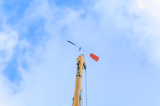 Sailboat mast with red Verklickerer against blue sky.