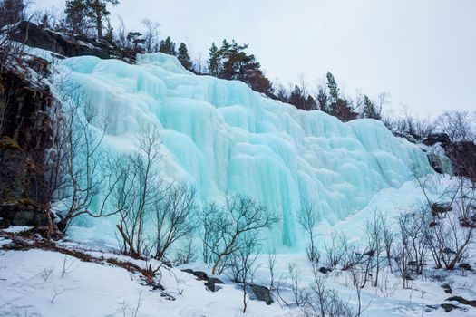 Blue ice and icicles at a frozen waterfall in Norway