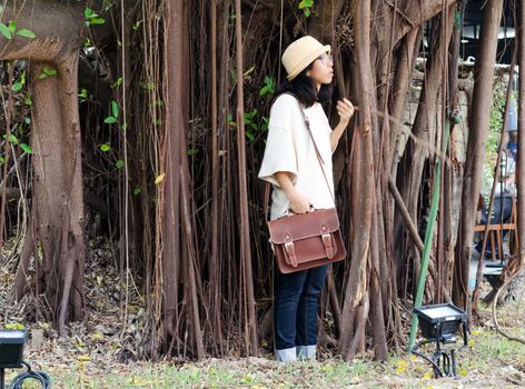 Fashion girl with handbag on banyan tree background