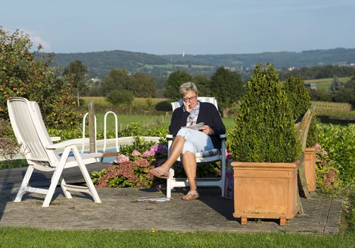 adult woman reading a book near the swimming pool and the belgium hills as background