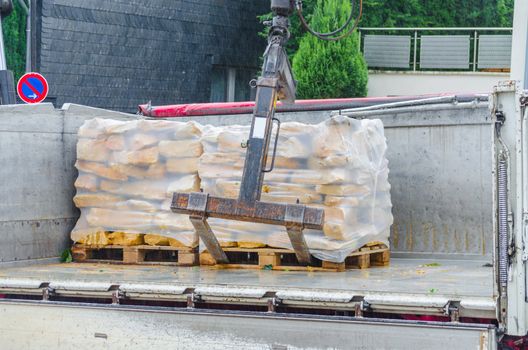 Pallets with sandstones are delivered and unloaded from a truck.