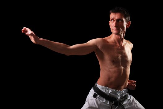 Karate. Man in a kimono with a black background
