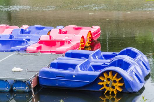 Red blue pedal boats at the dock for hire on the Ruhr in Essen Werden