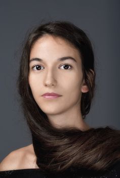 portrait of a woman with brown hair and brown eyes - isolated on gray